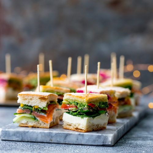 small sandwiches with toothpicks in them sitting on a marble board next to some lights