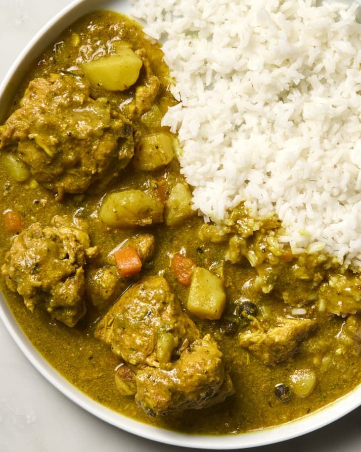 a white bowl filled with rice and meat stew next to another bowl full of food