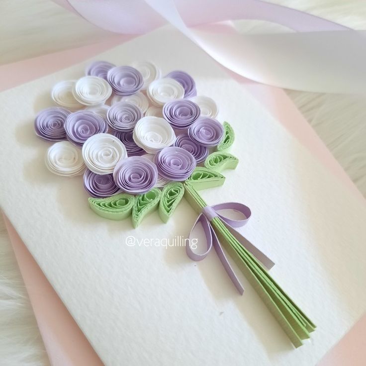 a bouquet of paper flowers sitting on top of a piece of white and purple paper