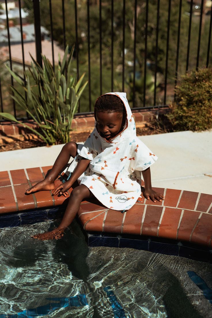 Arches features an arrow pattern in brown, red, and blue, with blue tassels at each corner of the hem of the poncho. Inspired by the end of summer and long days of games, running in the grass, and swimming in the pool for the last few times, this towel inspires us to get take advantage of the moment right now, and to have as much fun as we can today! No more oversized towels! No more mildew! No more sitting and shivering! Free your child to play unencumbered while wearing Kindhood Hooded Poncho Casual Hooded Poncho For Summer, Brown Summer Poncho For The Beach, Hooded Cotton Poncho For Summer, Traditional Cotton Poncho For The Beach, Traditional One Size Hooded Poncho, Traditional Hooded Winter Poncho, Surf Towel Poncho, Kids Towel Poncho, Collecting Shells