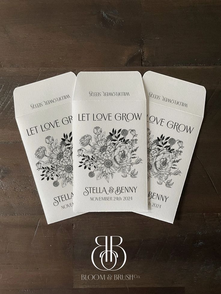 four white cards with flowers on them sitting on a wooden table next to the words let love grow written in black ink