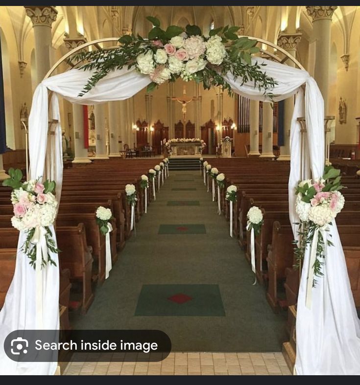 an aisle decorated with white flowers and greenery