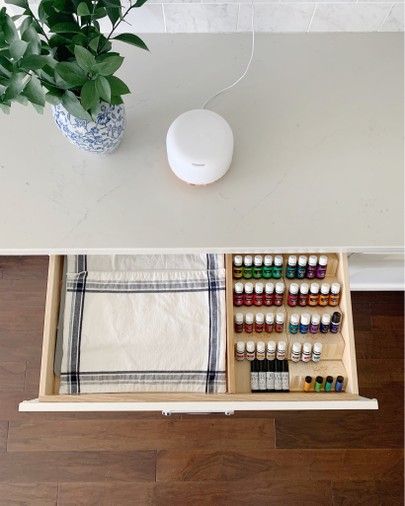 an open drawer with bottles and other items in it on a table next to a potted plant