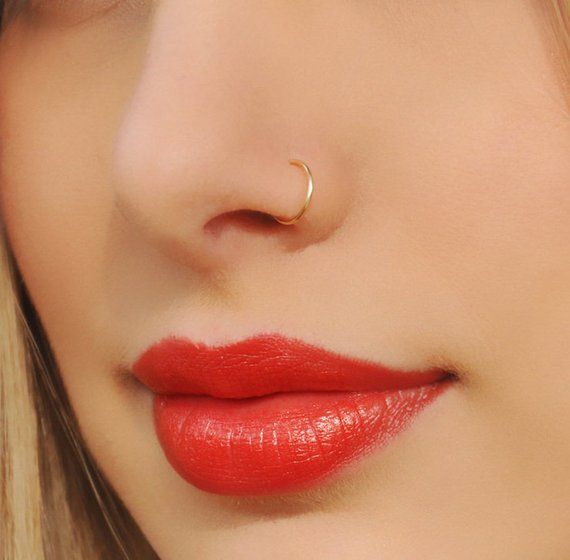 a close up shot of a woman with red lipstick and gold nose ring on her nose