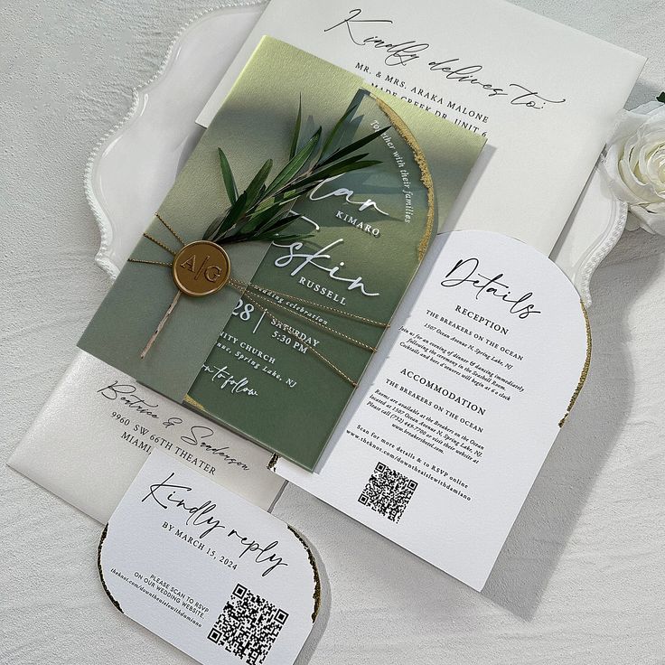 the wedding stationery is laid out on top of the table with white flowers and greenery