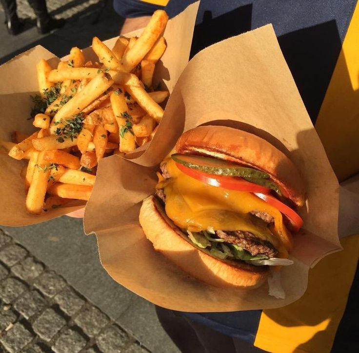 a person holding two sandwiches and french fries