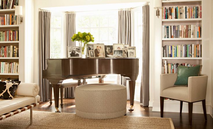 a living room filled with furniture and bookshelves next to a piano in front of a window