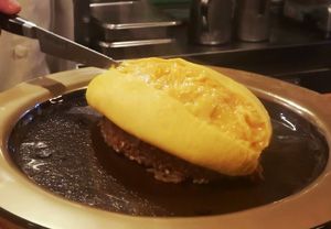 a person cutting into a hamburger on top of a metal pan with a knife in it