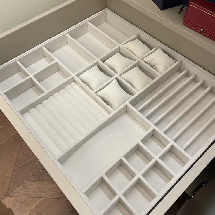 an open drawer with many compartments and pillows