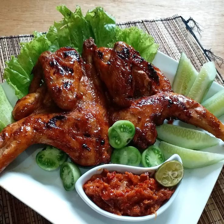 a white plate topped with chicken wings and vegetables