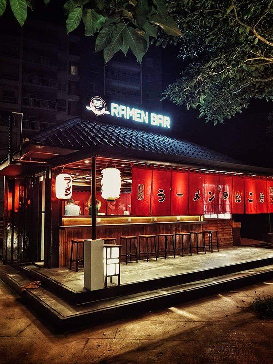 an outdoor bar with red walls and stools at night in front of a building