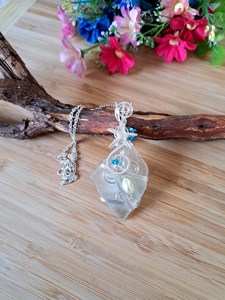 "Sea Glass Silver necklace, Handmade Beach Glass necklace, Sea Glass Jewellery, Unique gift for Her, Ocean Glass, Mermaid necklace, Boho gift 🎁  Beautiful piece of Natural Aqua Sea Glass pendant, wrapped on Silver plated wire, Blue Crystal beads, Pearl bead, Silver  plated Starfish Charm & 925 Silver plated chain 18\" 💝 This item is perfect gift idea for the Loved ones or for yourself, for Birthdays and any other special occasions.   The necklace come with gift bag ❤ FIND US: FACEBOOK at: www.facebook.com/foxjewelleryshop INSTAGRAM: www.instagram.com/Elevienn_ TWITTER: https://twitter.com/myotherhand CONTACT US: For any queries, please contact us via our shop or Facebook and we'll be happy to help. For any shipment queries,please refer to shipment policies. If you want any other shipment Clear Flower Pendant Necklace As Gift, Wire Wrapped Pendant Necklaces As Gifts, Wire Wrapped Pendant Necklace As Gift, Wire Wrapped Pendant Necklace For Gift, Unique Clear Jewelry For Gifts, Wire Wrapped Round Pendant Necklace As Gift, Unique Pendant Crystal Necklaces For Gifts, Handmade Teardrop Pendant Necklace For Wedding, Bohemian Clear Jewelry As A Gift