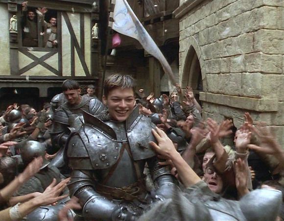 a group of people dressed in medieval armor and holding up their hands to the sky