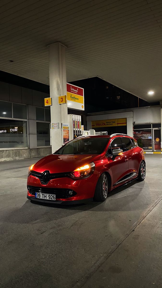 a red car parked in front of a gas station with no one around it at night