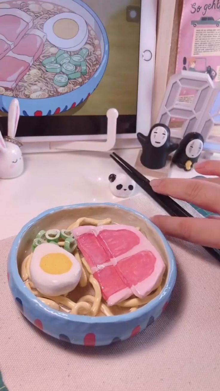 a person's hand is holding a small plate with food on it next to a computer