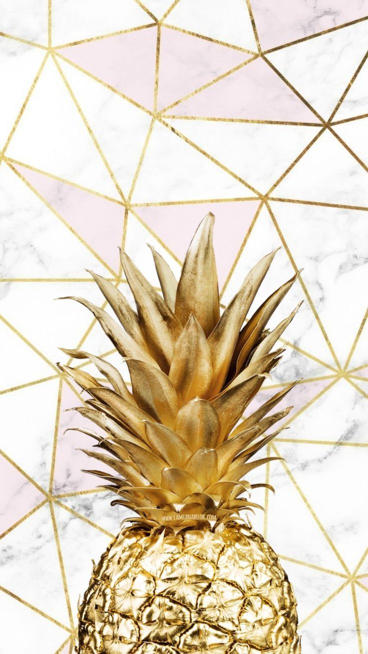 a golden pineapple sitting on top of a white marble counter next to a pink and gold geometric wall