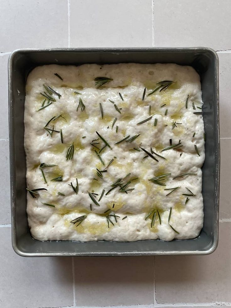 a pan filled with food on top of a white tile floor next to a tiled wall