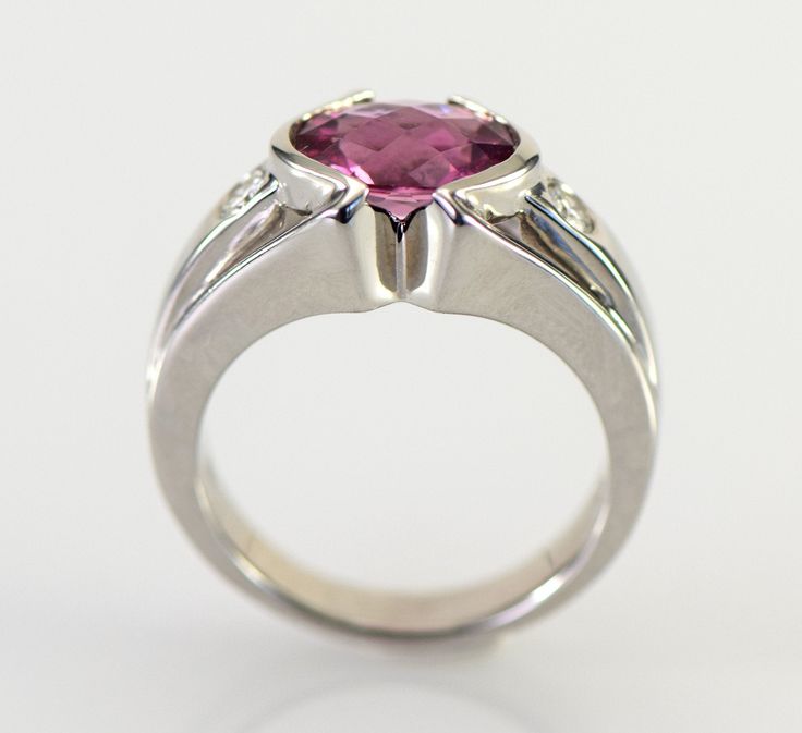 A dazzling pink Tourmaline checkerboard cut from Brazil is is accented with two flush set diamonds in this gorgeous 14k white gold ring. The natural Tourmaline is a 9 x 7 mm oval shape checkerboard cut and weighs 1.93 carats. The two diamonds are round brilliant cuts measuring 2.8mm with a total weight of .16 carats G-H color VS1-2 clarity The ring is 10.5 mm wide (3/8 inch) at the stone tapering down to 3.5 mm The height of the ring is 6 mm Ring weighs 7.31 grams Size 6 3/4 All items from Stowe Modern Tourmaline Wedding Rings, Pink Platinum Ruby Ring For Wedding, Pink Platinum Diamond Ring For Anniversary, Modern Pink Diamond Jewelry, Pink Sapphire Ring In Platinum For Anniversary, Pink Sapphire Platinum Ring For Anniversary, Pink Diamond Birthstone Ring For Formal Occasions, Pink Diamond Birthstone Ring For Formal Events, Pink Diamond Formal Birthstone Ring