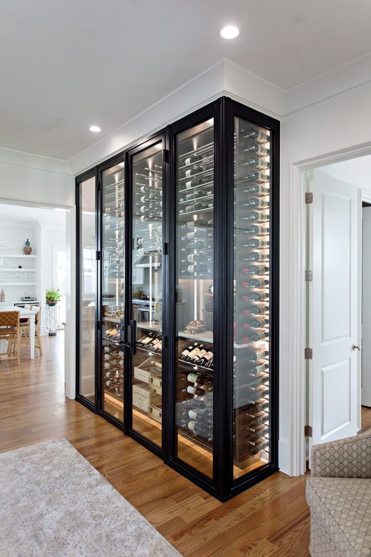 a wine cellar in the middle of a living room with hardwood floors and white walls