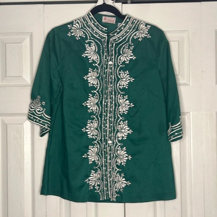 Prettiest shade of emerald green tunic embroidered around the neckline, front and sleeves. With pretty white pearlescent buttons down the front. A great addition to your wardrobe for summer.  Made to fit a bit loose. Made of 100% cotton. Fits a size M or L best.  Brand:  Shoje  Made in the Phillipines Spring Green Blouse With Intricate Embroidery, Spring Green Tunic With Chikankari Embroidery, Green Long Sleeve Top With Intricate Embroidery, Green Chikankari Embroidery Tunic For Spring, Green Chikankari Embroidered Tunic For Spring, Festive Green Top With Intricate Embroidery, Green Embroidered Hem Blouse For Spring, Summer Green Tops With Intricate Embroidery, Green Long Sleeve Embroidered Top