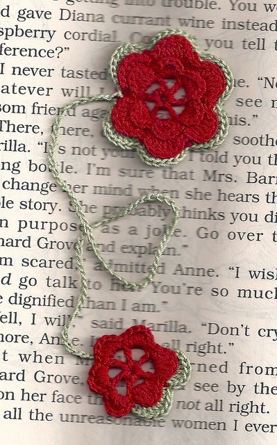 two crocheted red flowers sitting on top of an open book with the word love written