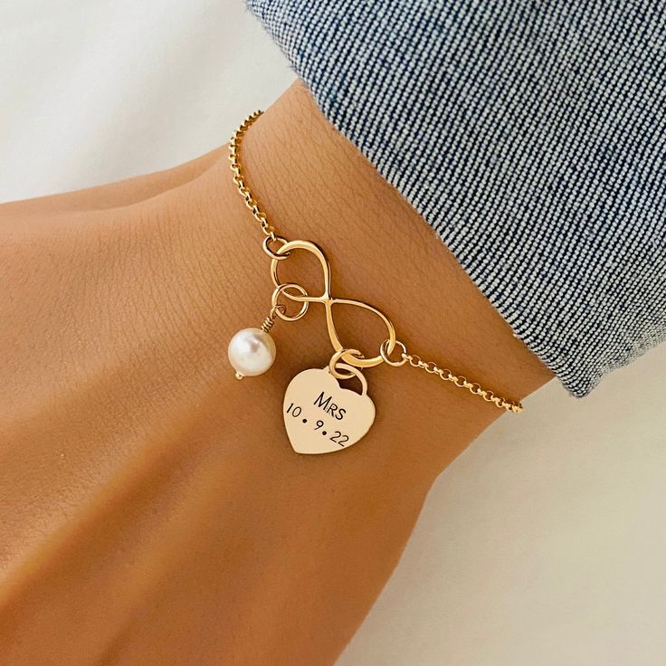 Personalised Bride Bracelet in Silver or Gold, Mrs Jewelry, Wedding Date Bracelet, Bridal Shower Gift, Infinity Knot, Pearl Bracelet ❤ Available in silver and gold. ❤ Specification: . Chain and components are 925 Sterling or 14K Gold Filled . Infinity is 925 Sterling Silver or Gold Vermeil with size 8 x 19mm . Heart Tag is 925 Sterling Silver or 14K Gold Filled with size 12mm . Swarovski Pearl size is 6mm . Length includes charm, jump ring and clasp . Comes in our signature satin pouch ready for gift giving ❤ All collections from StampedEve: https://www.etsy.com/au/shop/StampedEve?ref=hdr_shop_menu ❤ Please read my policies before ordering: https://www.etsy.com/au/shop/StampedEve/policy?ref=shopinfo_policies_leftnav IMPORTANT Usually jewellery in the pictures looks bigger than in reality. White Heart Bracelet For Wedding, White Heart-shaped Bracelet For Weddings, White Heart-shaped Pearl Bracelet For Wedding, White Heart-shaped Wedding Bracelet, White Pearl Wedding Bracelet For Valentine's Day, White Pearl Bracelet For Wedding And Valentine's Day, White Pearl Wedding Bracelet, Adjustable Pearl Bracelet For Wedding On Valentine's Day, Gold Bracelets For Wedding Gift On Mother's Day