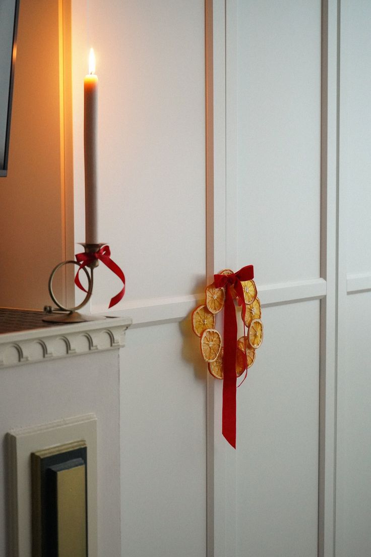 a candle is sitting on the wall next to a door with a ribbon tied around it