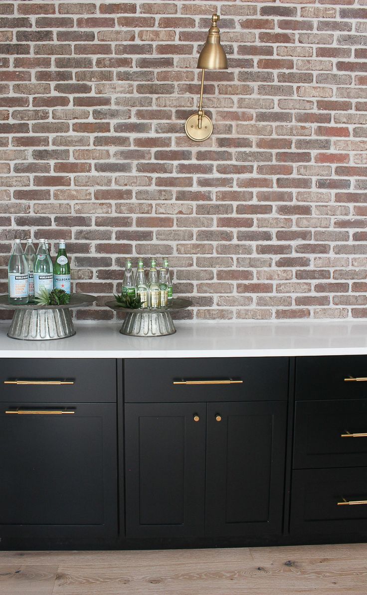 a kitchen with black cabinets and white counter tops, gold hardware on the bottom cabinet