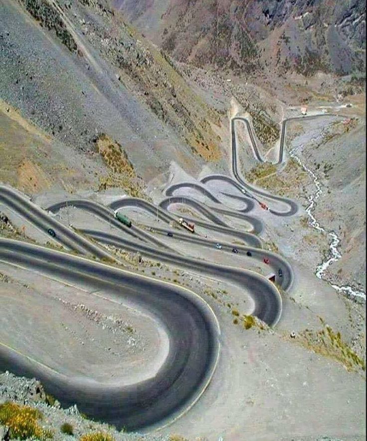 a winding road in the mountains with cars driving on one side and another going down the other