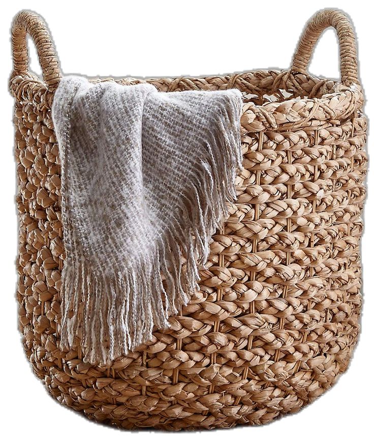 a woven basket with a white blanket on top and a gray towel hanging from the handle