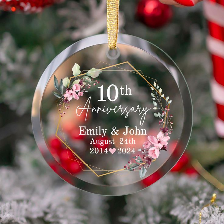 an ornament hanging from a christmas tree with flowers on it's side