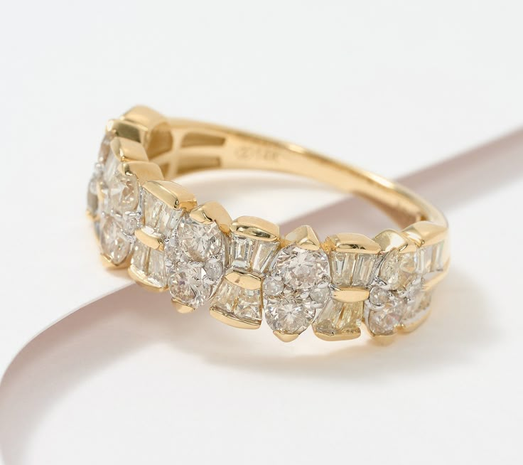 a yellow gold ring with five diamonds on it's sides, sitting on a white surface