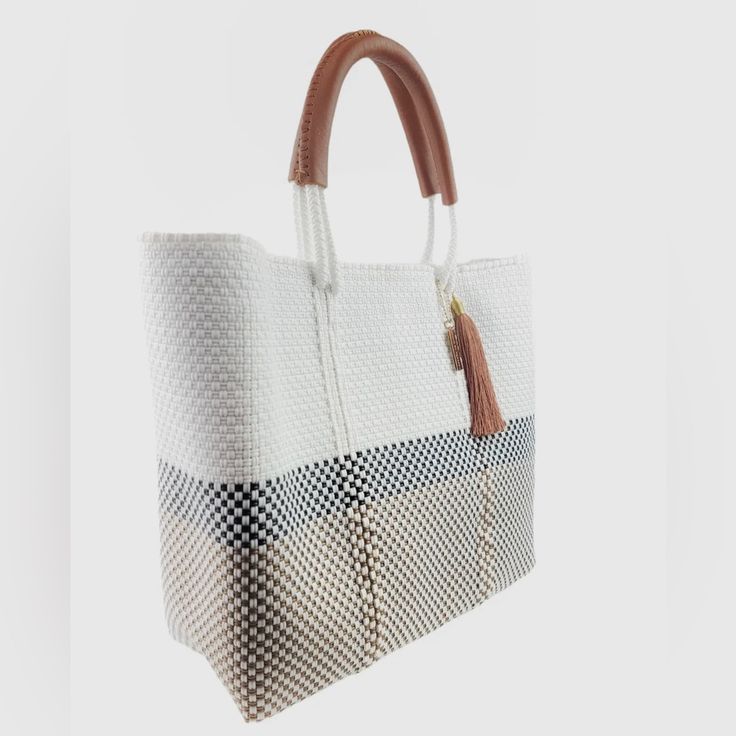 a white and black checkered bag hanging from a hook with a brown leather handle