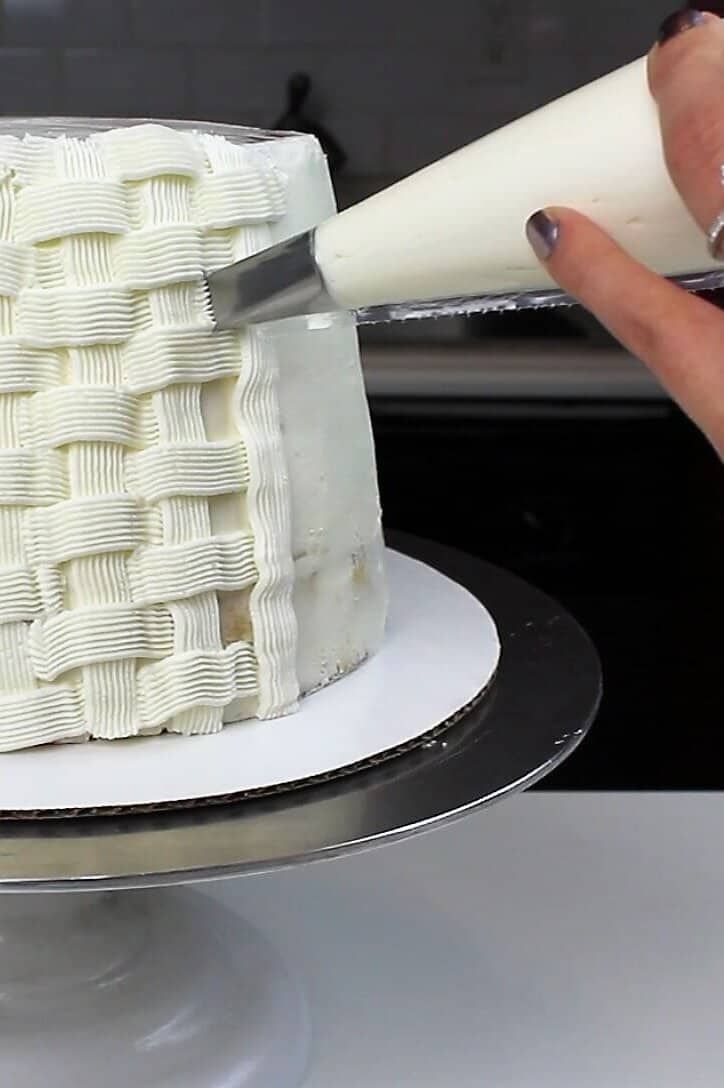 a woman is decorating a cake with white icing