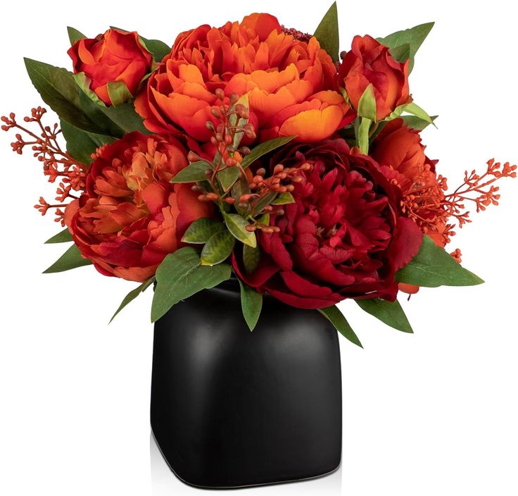 a black vase filled with red and orange flowers