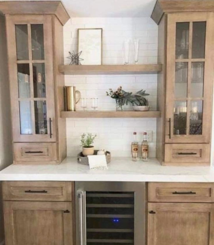 a kitchen with wooden cabinets and white counter tops, an open wine cooler in the middle