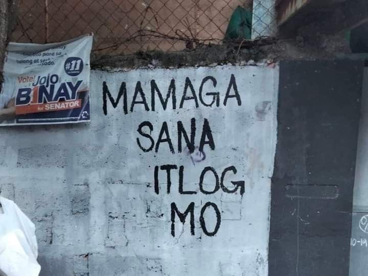 a man standing in front of a wall with graffiti on it that reads mamaga sana tilog mo