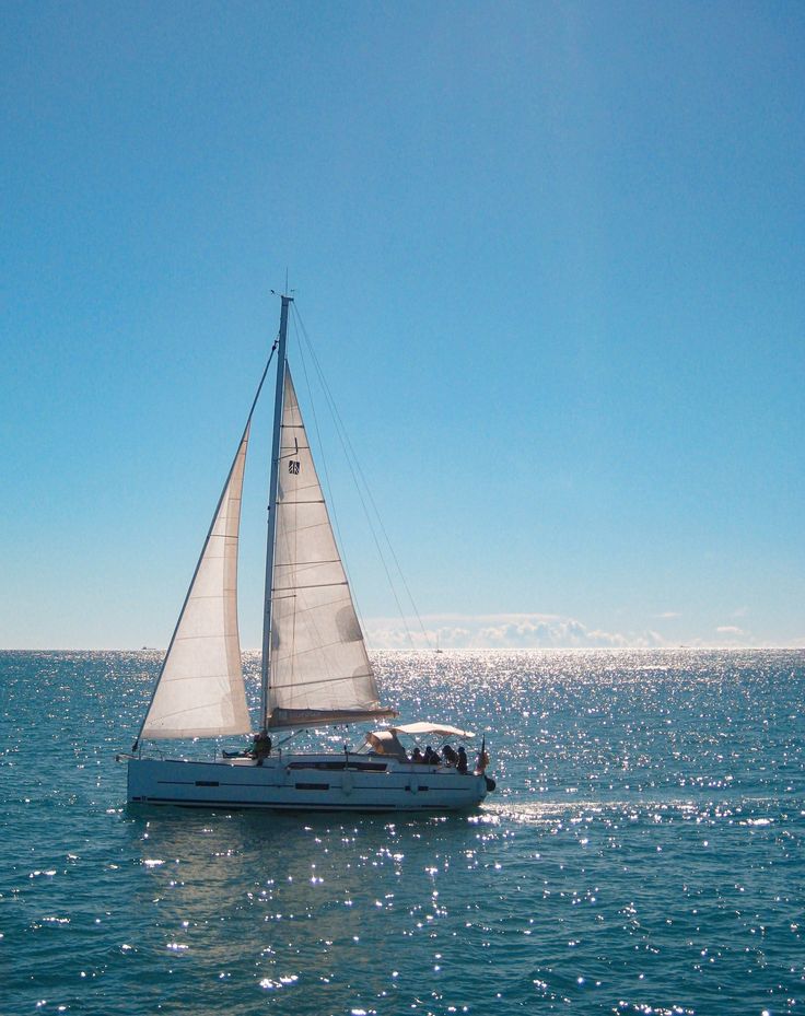 a sailboat sailing in the ocean on a sunny day