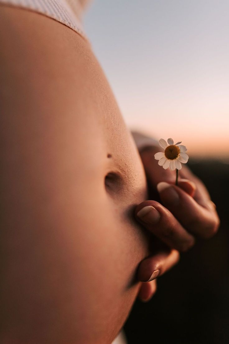 a pregnant woman holding a flower in her belly