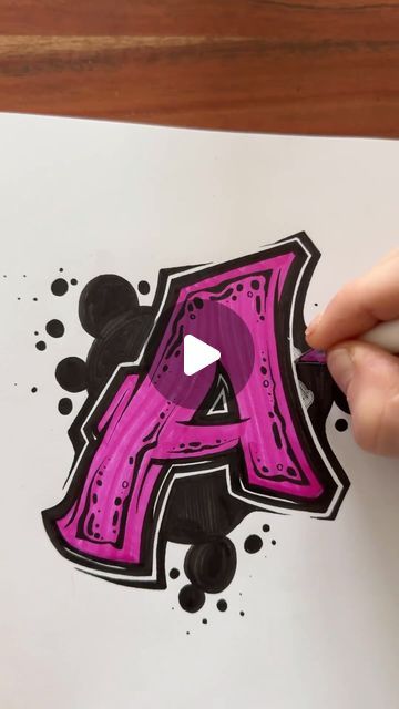 someone is drawing the letter a with black and pink ink