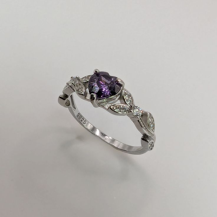 Brilliant sparkle with a lush Amethyst Cubic Zirconia heart shaped stone, this White Gold Amethyst engagement ring has a core of solid 925 Sterling Silver, making it hypoallergenic and built to last! The high-quality faceted heart stone is 6mm (0.8 carat) and has a Mohs hardness of 8-1/2. Sprinkled generously with cubic zirconia rhinestones, this lovely Amethyst ring is accented by a nature-inspired tree branch and leaf design.It would make a great promise ring or engagement ring, as well as an Heart Cut Amethyst Ring With Accent Stones, Heart-shaped Amethyst Wedding Ring In Fine Jewelry Style, Heart-shaped Amethyst Ring For Wedding, Fine Jewelry, Heart Shaped Amethyst Ring For Wedding, Heart-shaped Amethyst Wedding Ring, Silver Heart Cut Amethyst Ring Gift, Silver Amethyst Heart Cut Ring Gift, Brilliant Cut Amethyst Diamond Ring Gift, Gift Amethyst Diamond Ring With Brilliant Cut