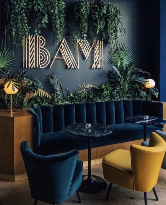 the interior of a restaurant with blue walls and green plants on the wall, along with yellow chairs