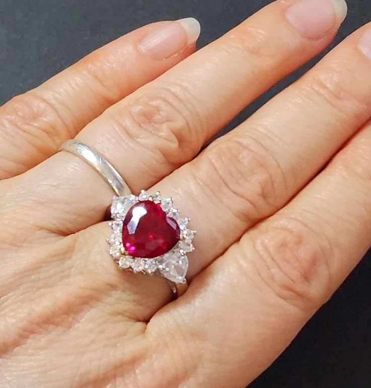 Sterling silver ring with ruby red heart.  * Metal: 925 sterling silver * Stone type: Synthetic  * Stone color: Garnet or Ruby red * Weight: 6.2 grams * Center stone size: 10mm * Stamp: 925 * Ring band width at back of ring: 3mm * The three main prongs are gold-plated This makes a great gift for Valentine's Day, Mother's Day or birthdays. Gift for women.  Ruby is the birthstone for July birthdays. sterling silver heart rings for women Save with combined shipping. See our other heart jewelry here Classic Silver Ruby Ring For Valentine's Day, Red Heart Ring With Center Stone, Red Heart-shaped Rings With Center Stone, Ruby Gemstone Rings For Valentine's Day, Ruby Heart Cut Rings For Valentine's Day, Ruby Heart Ring With Gemstone, Red Heart Ring For Anniversary In Fine Jewelry Style, Red Heart Ring For Anniversary, Fine Jewelry, Fine Jewelry Red Heart Ring For Anniversary