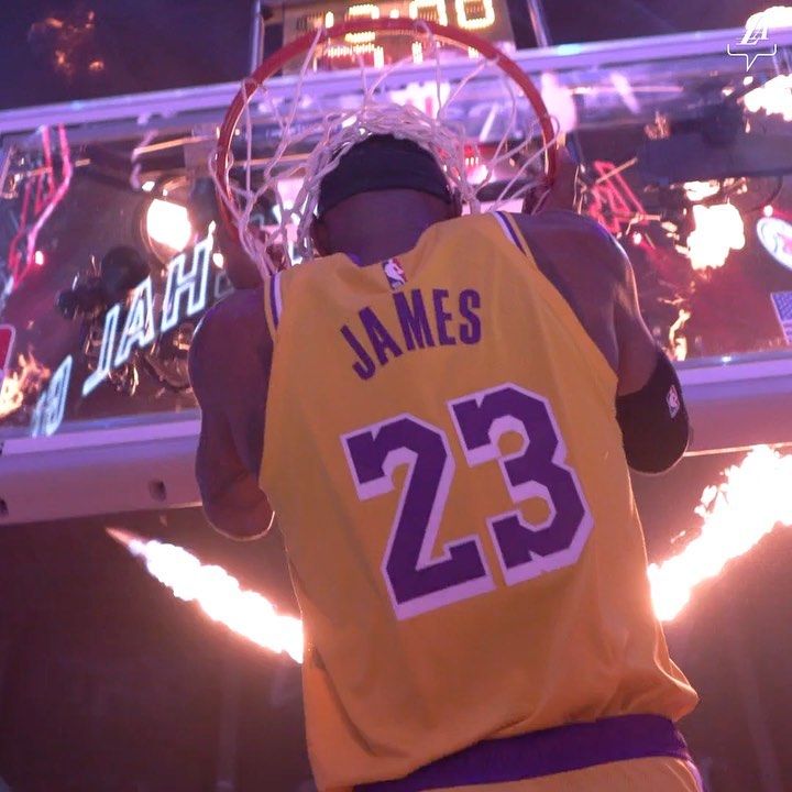 a basketball player is in the air with his back to the camera while holding a hoop