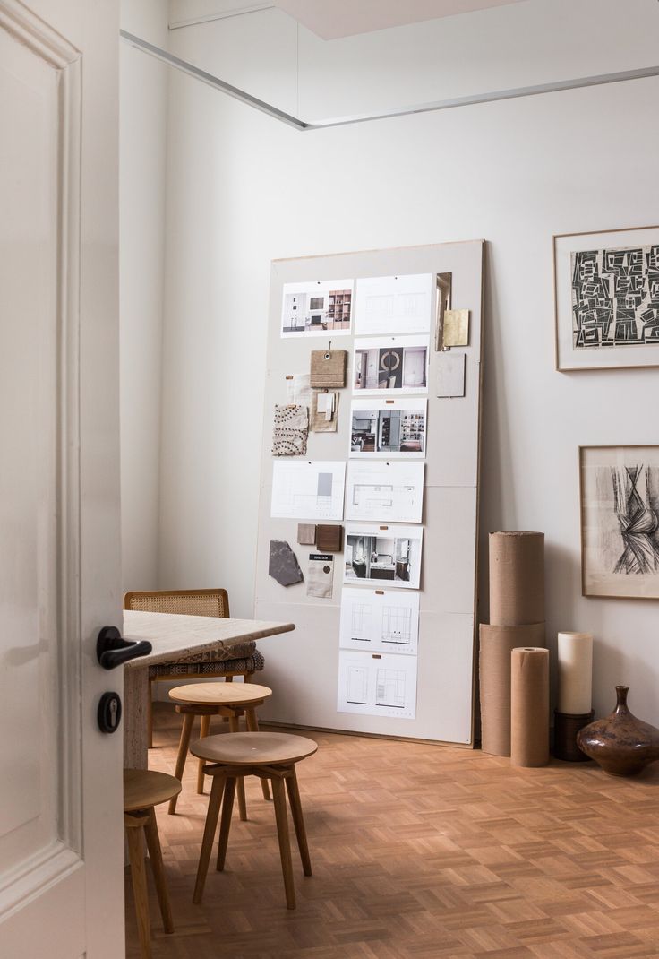 a white room with wooden floors and pictures on the wall, including two stools