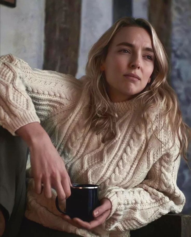 a woman sitting on a couch holding a cup