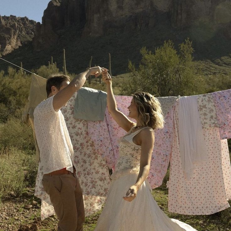 a man and woman standing next to each other in front of clothes hanging on a line