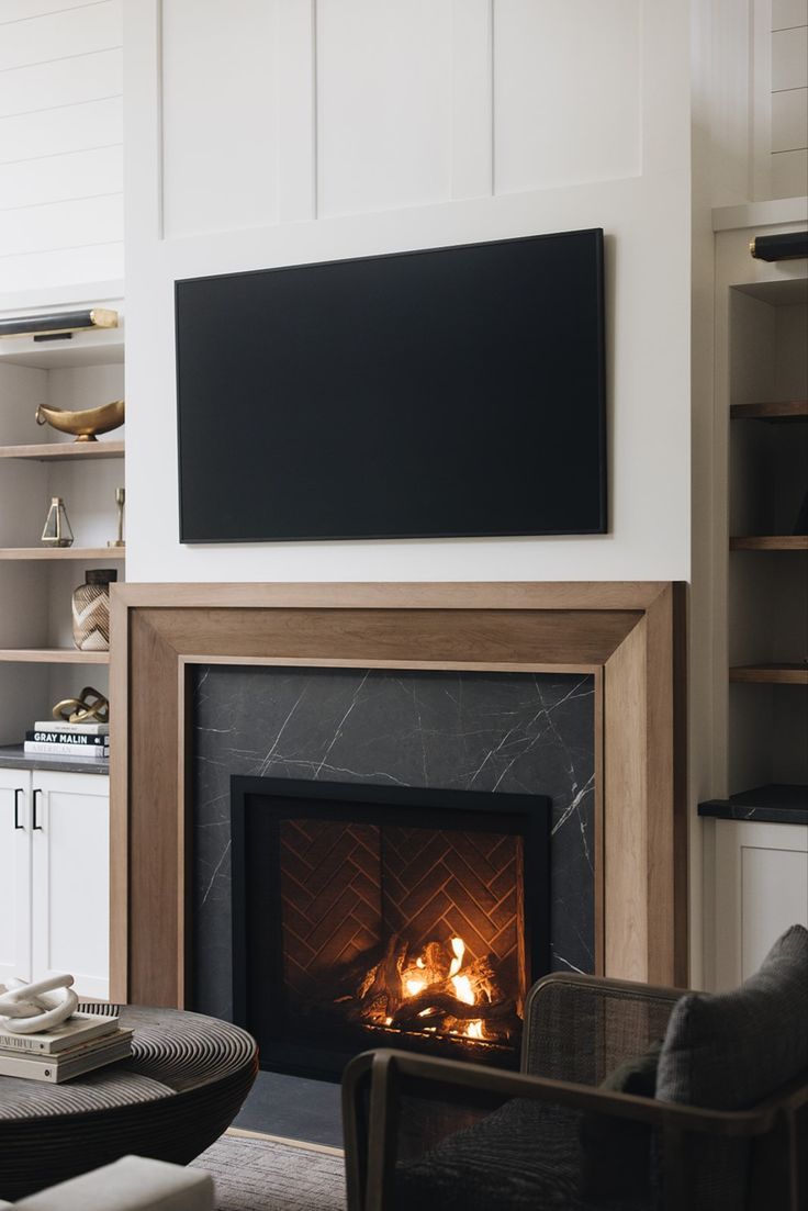 a living room with a fire place in the center and a flat screen tv above it