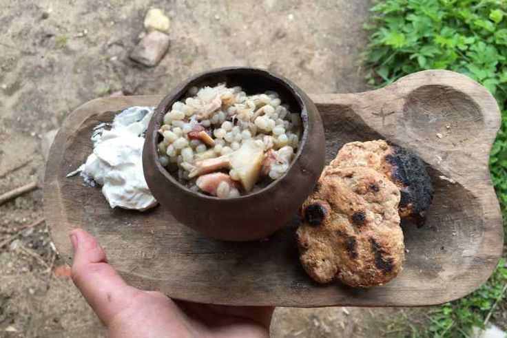 a person holding a wooden tray with food on it and a cookie in the other hand