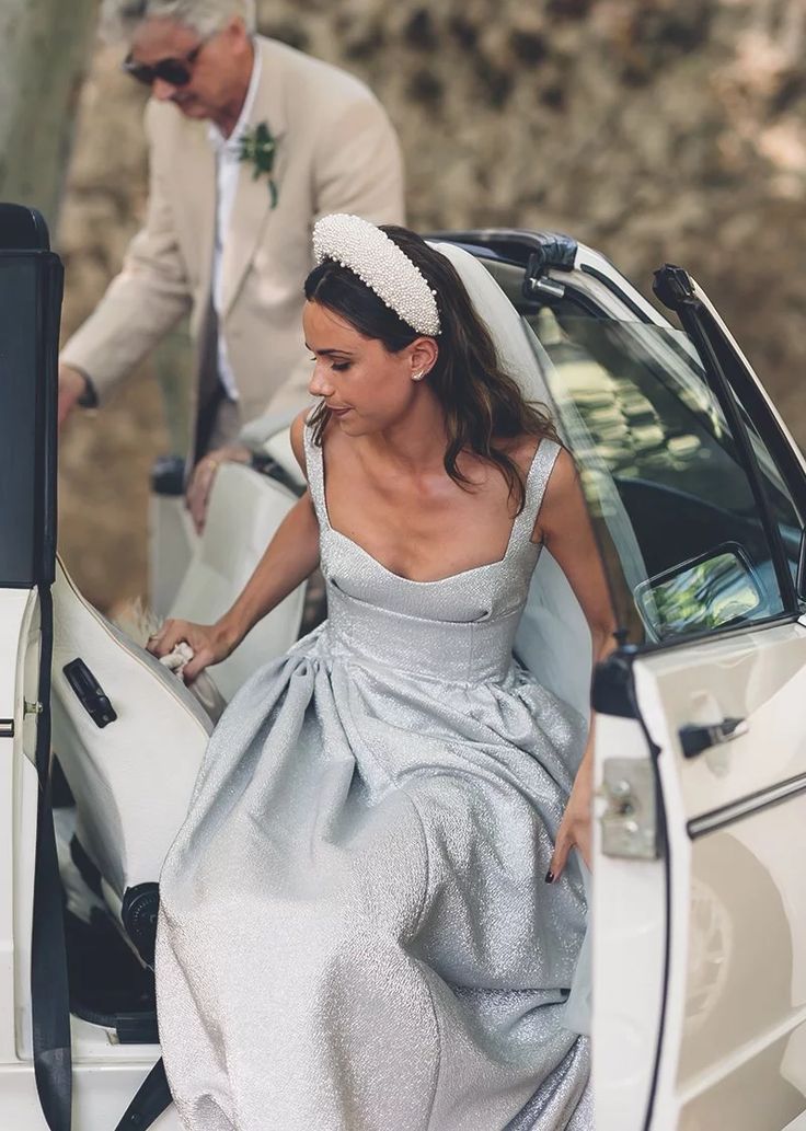 a woman in a silver dress getting out of a car